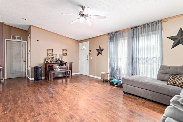 living room featuring ceiling fan, a textured ceiling, dark hardwood / wood-style floors, and ornamental molding