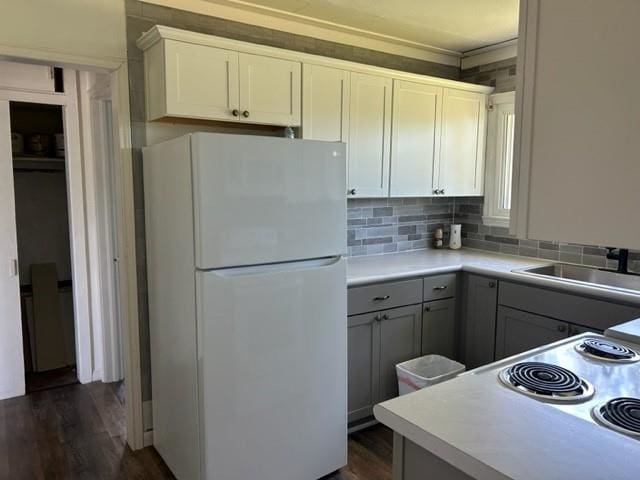 kitchen with white cabinets, white fridge, dark hardwood / wood-style flooring, and sink