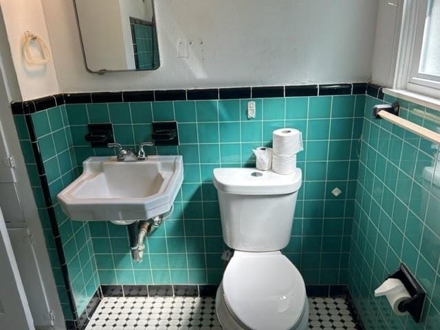 bathroom featuring tile patterned flooring, toilet, tile walls, and sink