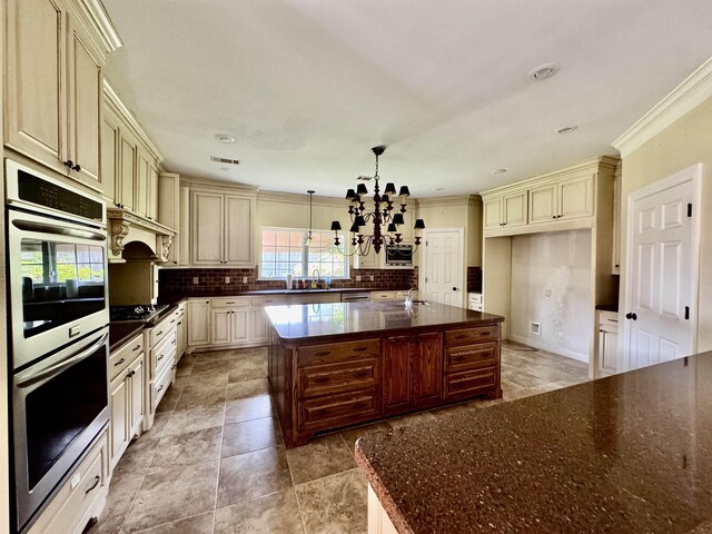 6400 Chasse Gdns, Little Cypress, TX 77632 - kitchen with cream cabinetry, double oven, a chandelier, decorative backsplash, and crown molding
