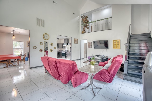 1062 Bassett St, Orange, TX 77632 - living room with light marble finish floors, stairway, a towering ceiling, and baseboards
