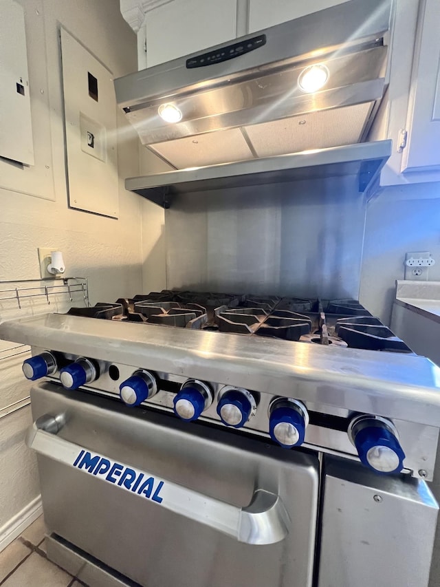 kitchen featuring white cabinets, light tile patterned flooring, high end range, and electric panel