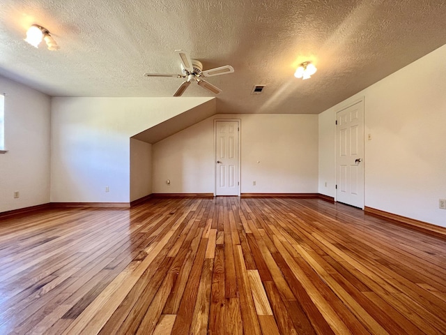 additional living space with ceiling fan, light hardwood / wood-style floors, and a textured ceiling