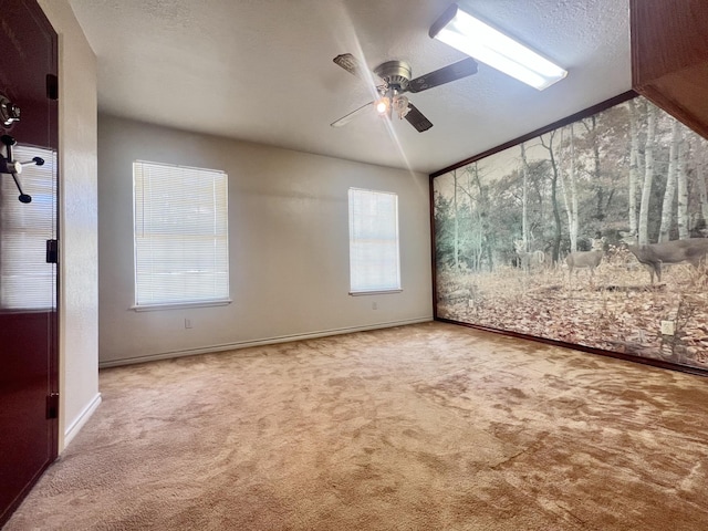 unfurnished room with carpet flooring, ceiling fan, and a wealth of natural light