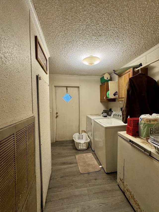 washroom with washer and dryer, cabinets, wood-type flooring, and a textured ceiling