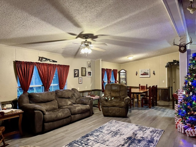 living room with ceiling fan, crown molding, wood-type flooring, and a textured ceiling