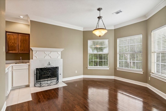 unfurnished living room featuring ornamental molding, a fireplace, sink, and light hardwood / wood-style flooring