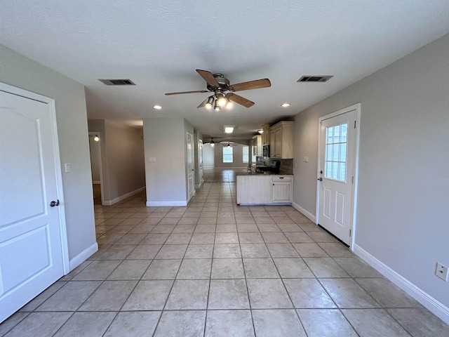 kitchen with ceiling fan, light tile patterned floors, a textured ceiling, and a wealth of natural light