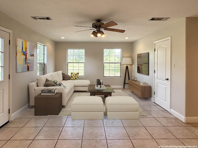 living room featuring ceiling fan, light tile patterned floors, and a textured ceiling