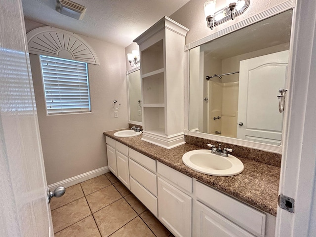 bathroom featuring tile patterned flooring, vanity, a shower, and a textured ceiling