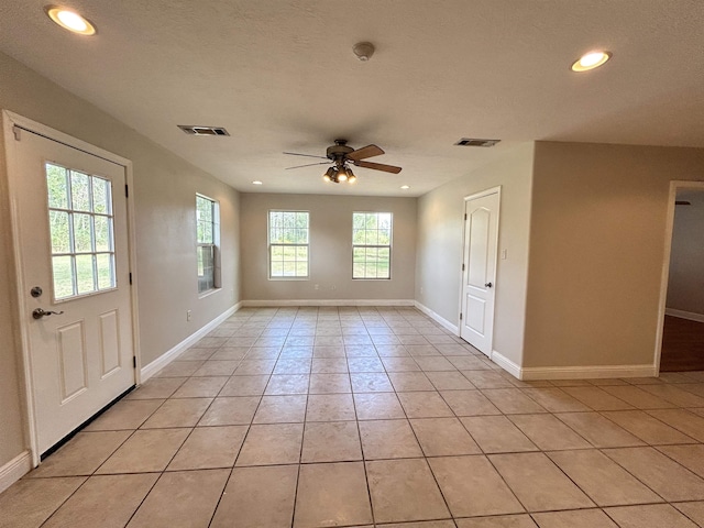 tiled empty room featuring ceiling fan