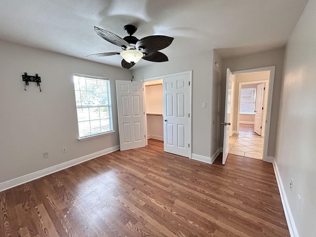 unfurnished bedroom with ceiling fan, a closet, and wood-type flooring