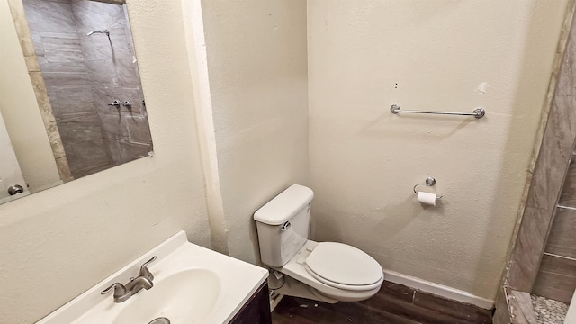 full bathroom featuring a textured wall, toilet, vanity, wood finished floors, and baseboards