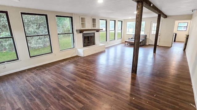 unfurnished living room featuring dark wood-style floors, beam ceiling, a fireplace, recessed lighting, and baseboards