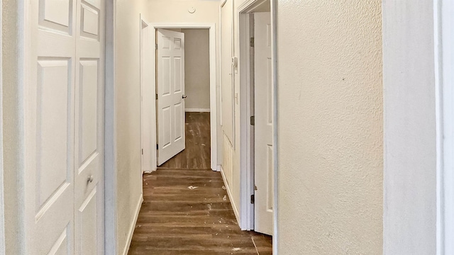 hallway with dark wood-style floors and a textured wall