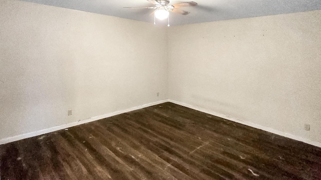 spare room featuring ceiling fan, dark wood finished floors, and baseboards