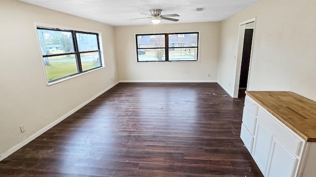 spare room with ceiling fan, dark wood-type flooring, plenty of natural light, and baseboards