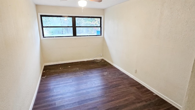 empty room featuring dark wood finished floors, baseboards, and ceiling fan