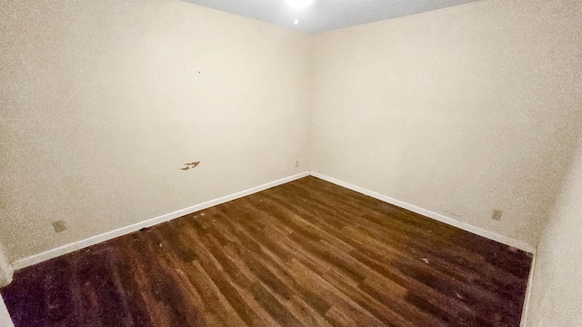 empty room featuring dark wood-style floors and baseboards