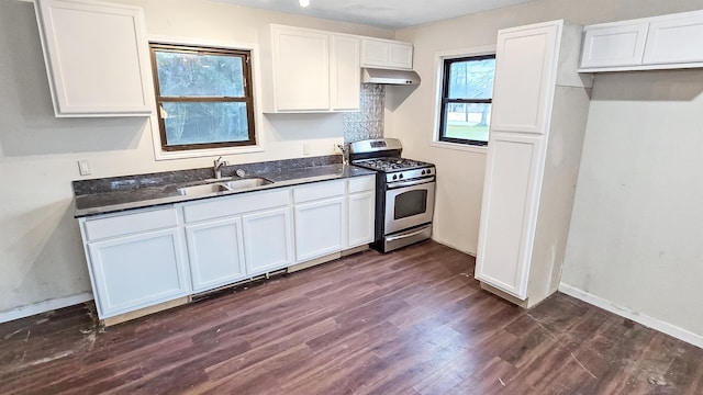 kitchen featuring dark countertops, stainless steel gas range, under cabinet range hood, and a sink