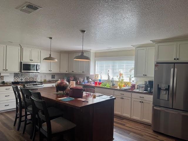 kitchen with dark wood finished floors, appliances with stainless steel finishes, visible vents, and a kitchen island