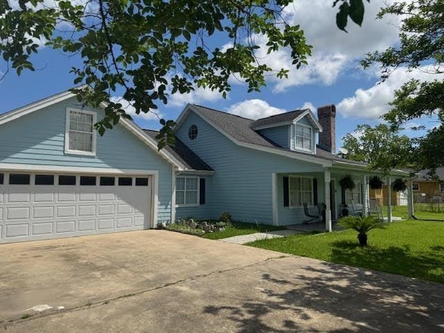 view of front of home with concrete driveway, an attached garage, a front lawn, and a chimney