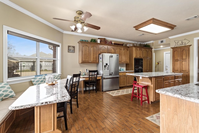 302 Waterwood Dr, Orange, TX 77630 - kitchen with black appliances, a breakfast bar, a center island with sink, crown molding, and dark wood-type flooring