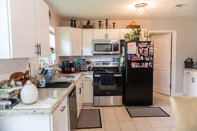 kitchen featuring white cabinets, decorative backsplash, light tile patterned flooring, and stainless steel appliances