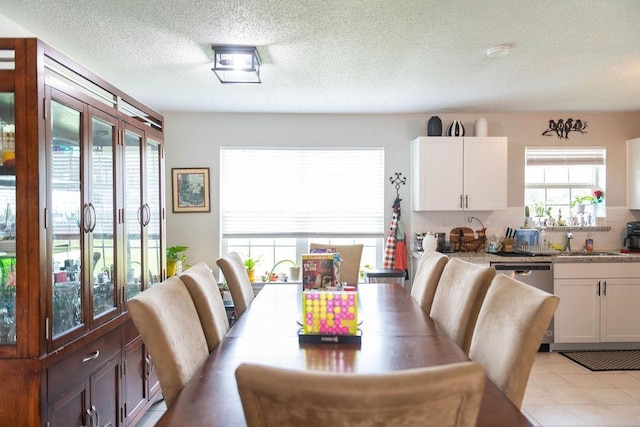 tiled dining room featuring a textured ceiling, a healthy amount of sunlight, and sink