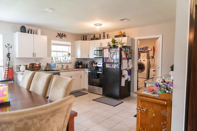 kitchen featuring sink, light tile patterned floors, white cabinetry, stainless steel appliances, and washer / clothes dryer