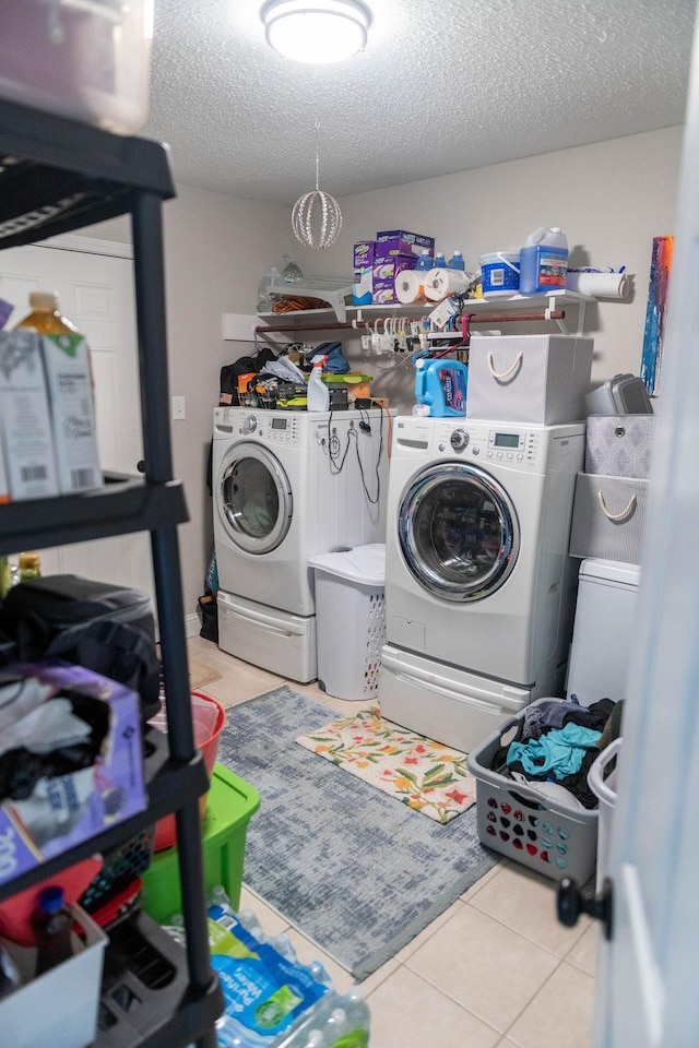 laundry room with washing machine and clothes dryer, light tile patterned floors, and a textured ceiling