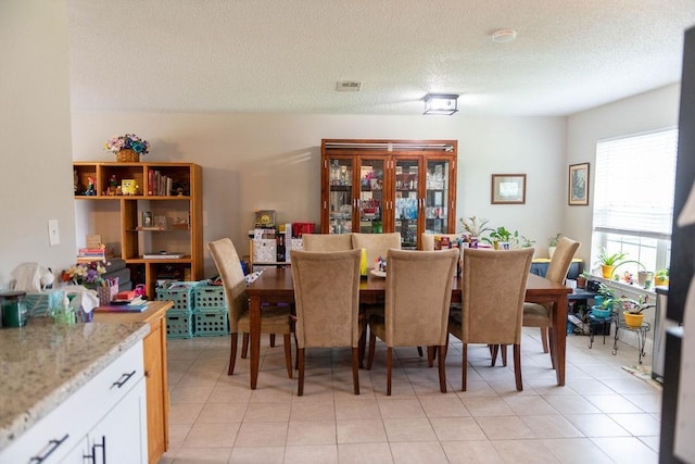 dining space with light tile patterned flooring and a textured ceiling