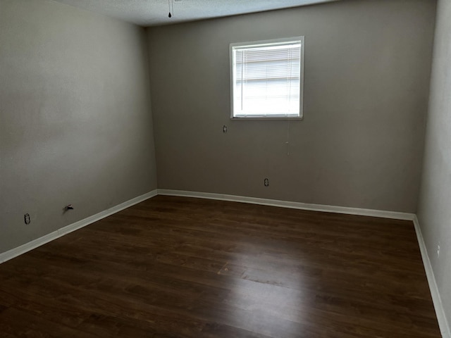 empty room featuring a textured ceiling and dark hardwood / wood-style floors