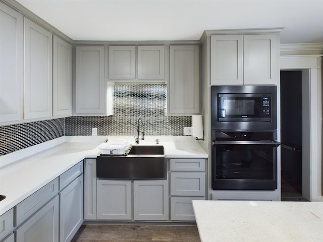 kitchen featuring gray cabinets, oven, built in microwave, and sink