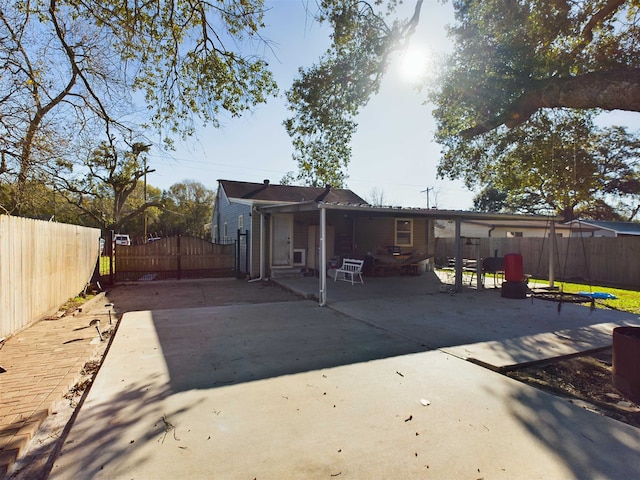 rear view of property featuring a trampoline and a patio area