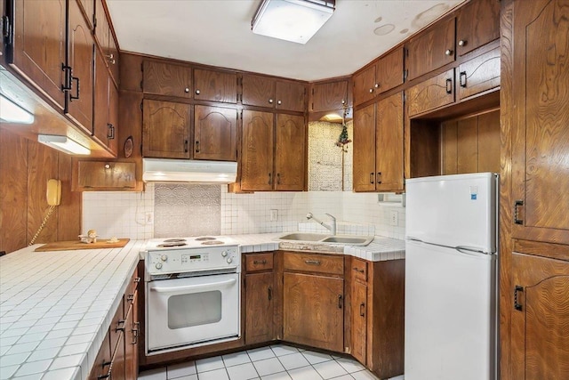 kitchen featuring tile counters, sink, backsplash, white appliances, and light tile patterned floors