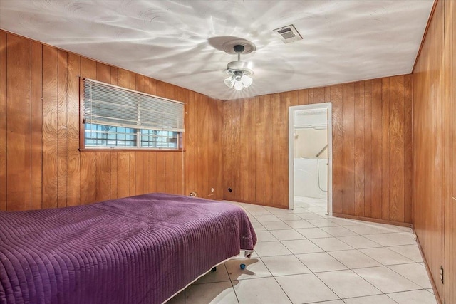 bedroom featuring light tile patterned floors, ceiling fan, and wood walls