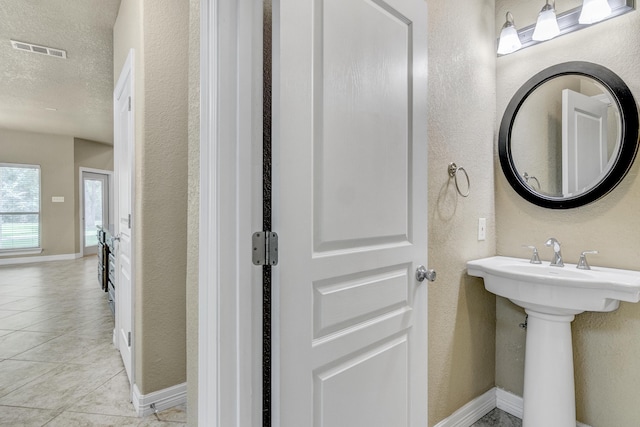 bathroom featuring a textured ceiling, tile patterned floors, and sink