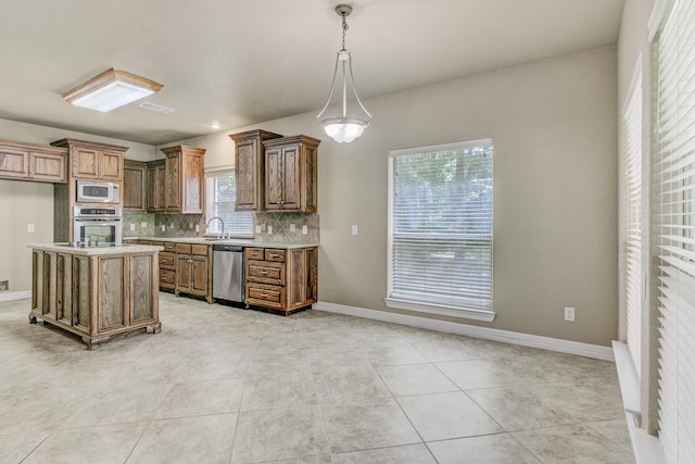 kitchen with a center island, light tile patterned floors, appliances with stainless steel finishes, tasteful backsplash, and decorative light fixtures