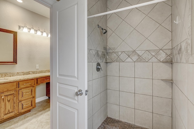 bathroom featuring a tile shower, vanity, and tile patterned floors