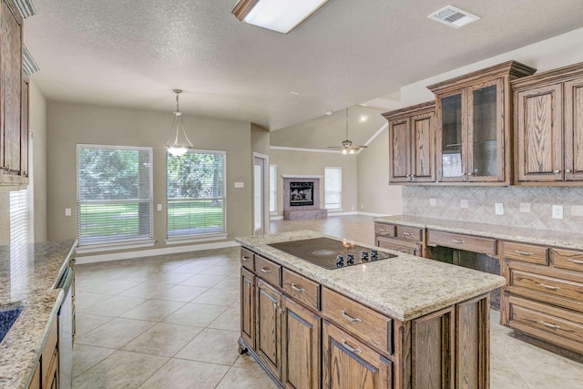 kitchen featuring backsplash, black electric cooktop, ceiling fan, light tile patterned floors, and decorative light fixtures