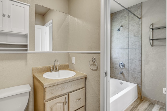 full bathroom with tiled shower / bath combo, toilet, wood-type flooring, and vanity