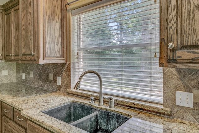 kitchen featuring backsplash, light stone counters, and sink