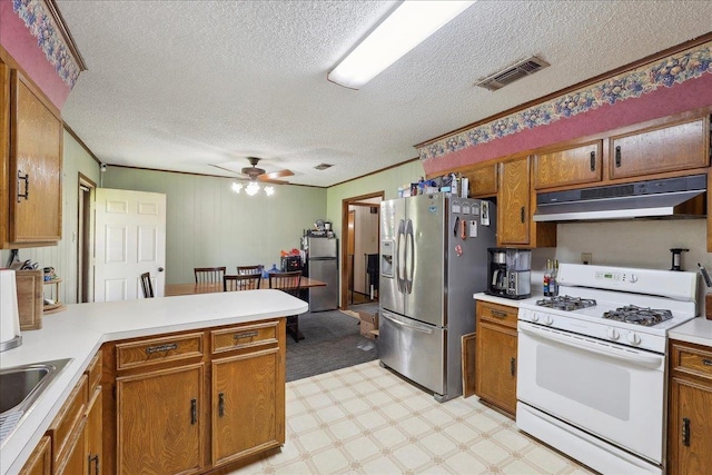 kitchen with under cabinet range hood, white gas stove, light floors, freestanding refrigerator, and stainless steel refrigerator with ice dispenser