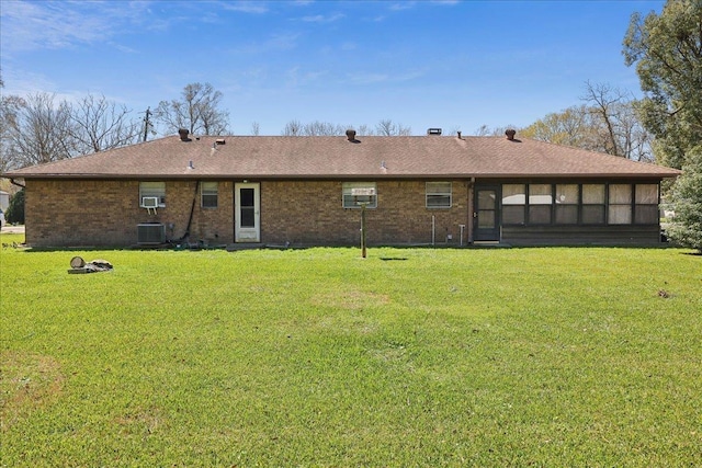 back of house featuring a yard, cooling unit, brick siding, and a sunroom