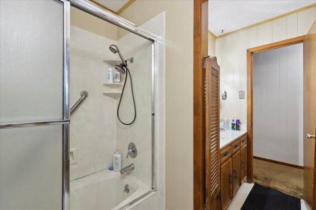 full bathroom with a textured ceiling, combined bath / shower with glass door, wooden walls, crown molding, and vanity