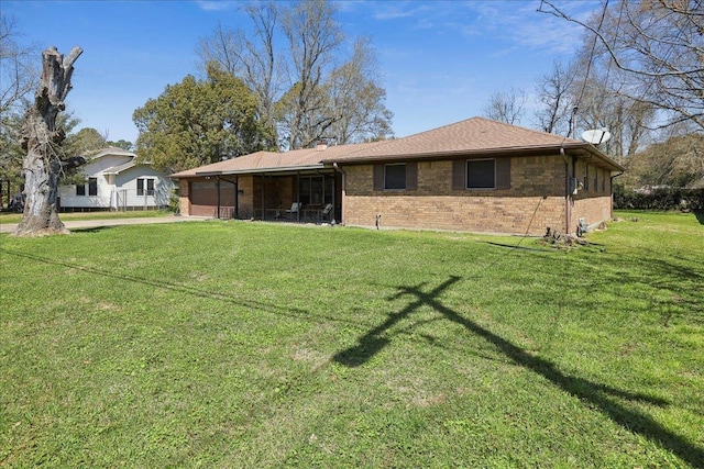 back of property with a chimney, concrete driveway, a garage, a lawn, and brick siding