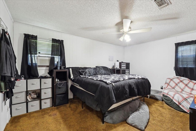 bedroom with visible vents, carpet floors, cooling unit, a textured ceiling, and a ceiling fan