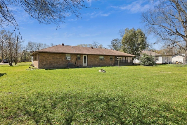 rear view of property with a yard, brick siding, and central AC unit