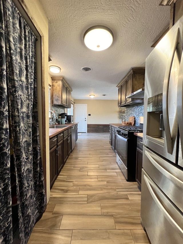 kitchen featuring tasteful backsplash, dark brown cabinetry, sink, and stainless steel appliances